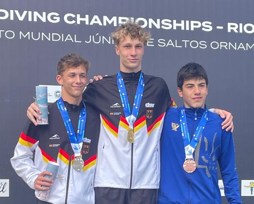 Die Nachwuchs-Wasserspringer Finn Awe (Gold) und Louis Aaron Förster (Silber) aus Deutschland stehen bei der Junioren-WM 2024 in Rio de Janeiro bei der Siegerehrung vom 1m-Brett auf dem Siegerpodest zusammen mit einem Springer aus der Ukraine