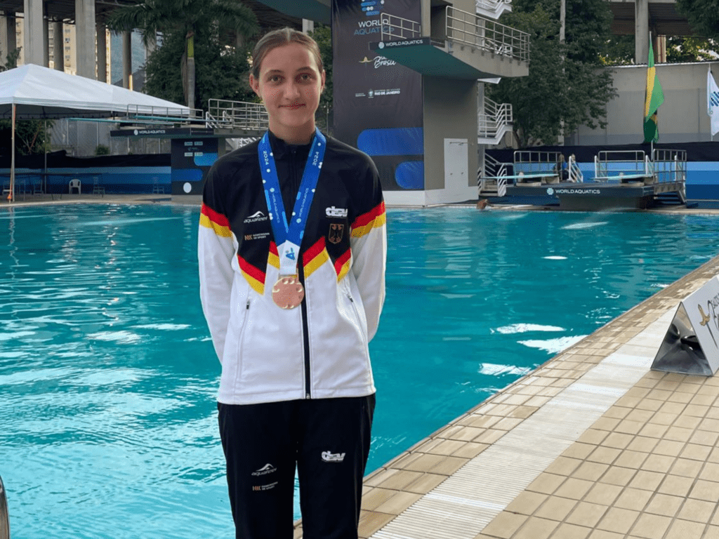 Wasserspringerin Nina Berger aus Aachen posiert am Beckenrand mit ihrer Bronzemedaille vom 3m-Brett bei der WM der Juniorinnen 2024 in Rio de Janeiro