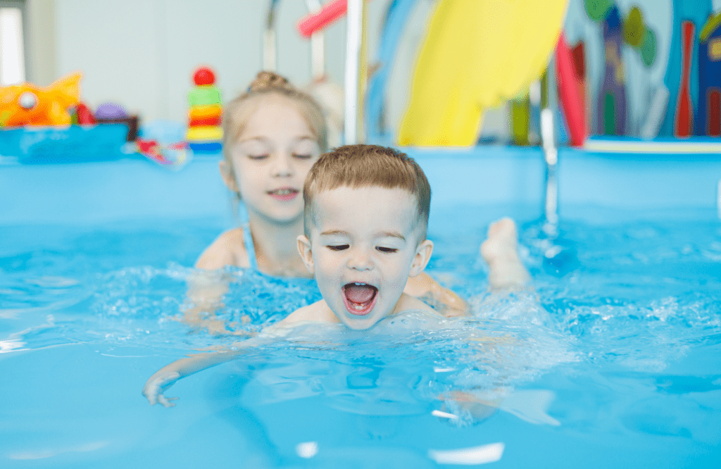 Zwei Kinder beim Schwimmkurs der Junge lacht begeistert