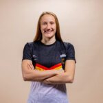 Die Schwimmerin Jeannette Spiwoks steht vor einer beigen Leinwand zum Porträtfoto
