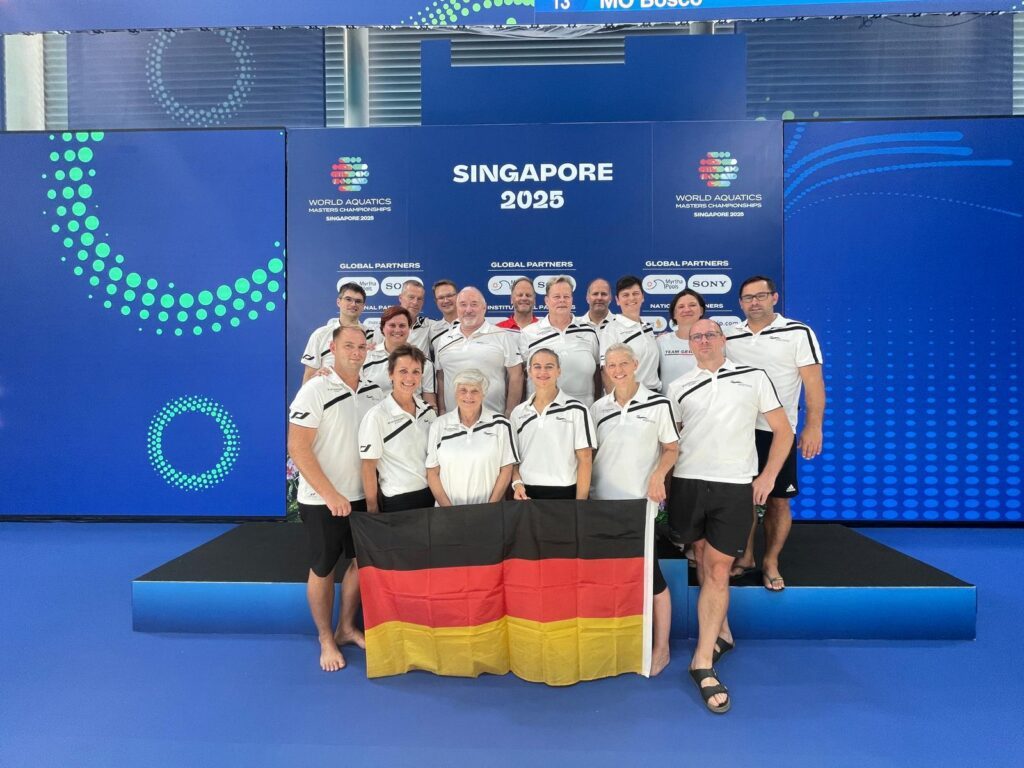 Gruppenbild deutscher Wasserspringer*innen bei der Masters-WM 2025 in Singapur mit Deutschlandfahne
