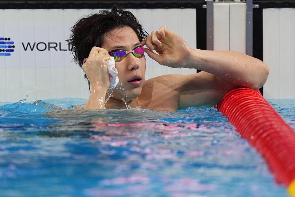 Schwimmer Qin Haiyang aus China nimmt bei der Kurzbahn-WM 2024 in Budapest noch im Becken seine Schwimmbrille ab nach seinem Sieg über 50m Brust