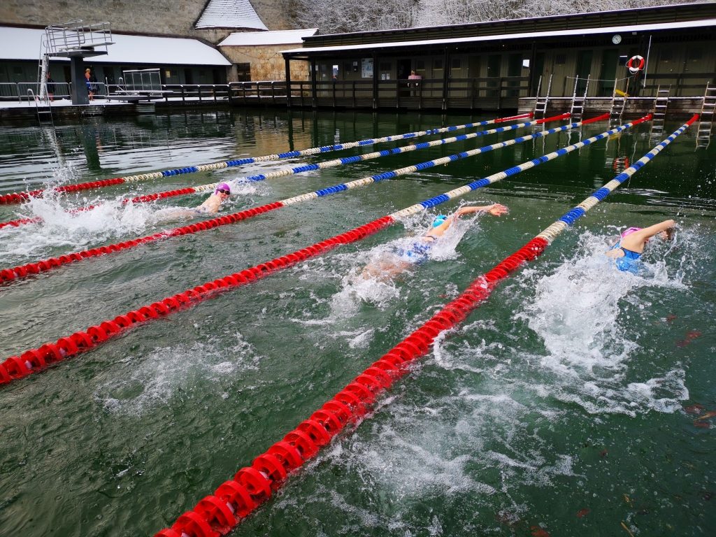 Eisschwimmerinnen schwimmen in Burghausen unterhalb der Burg im kalten Wasser