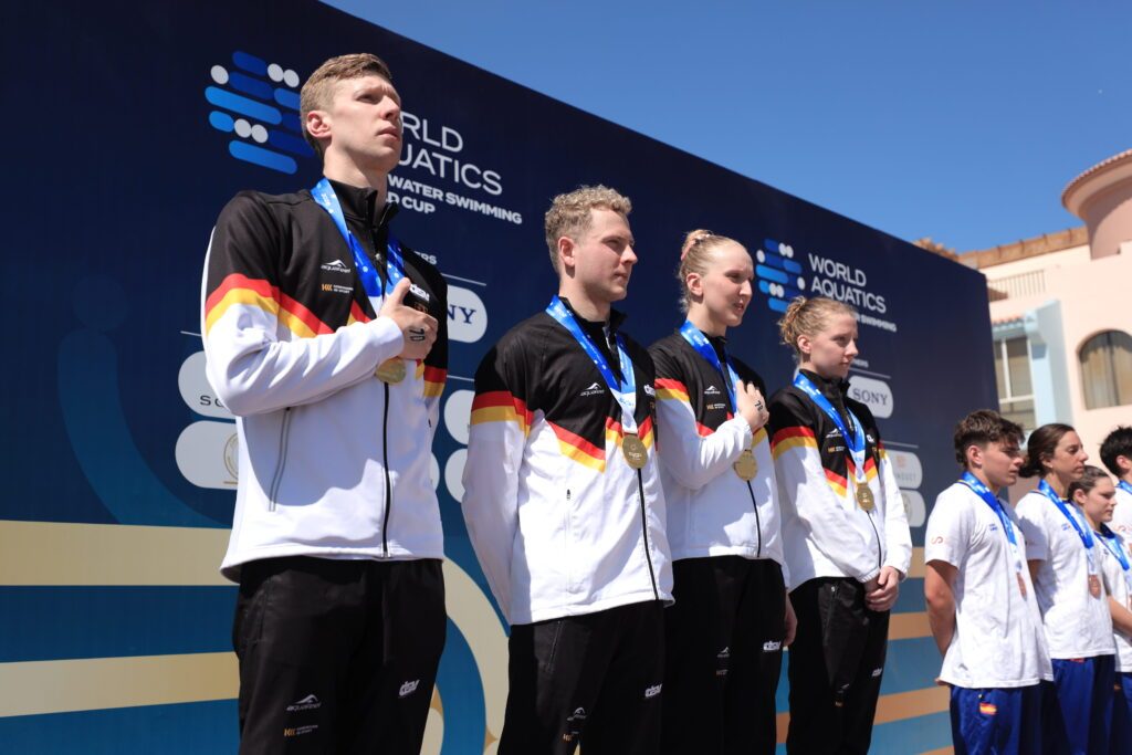 Florian Wellbrock, Oliver Klemet, Leonie Märtens und Lea Boy (v.l.) lauschen der deutschen Hymne bei der Siegerehrung