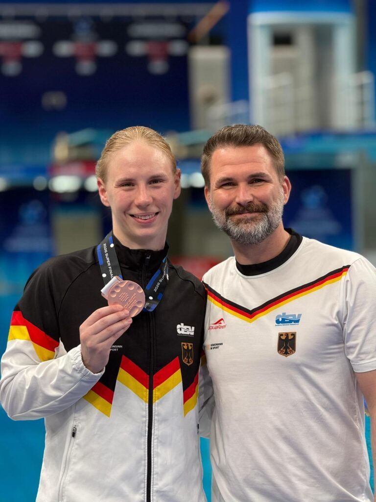 Turmspringerin Pauline Pfeif aus Deutschland mit Trainer Christoph Bohm und der Bronzemedaille beim Weltcupfinale 2026 in Peking