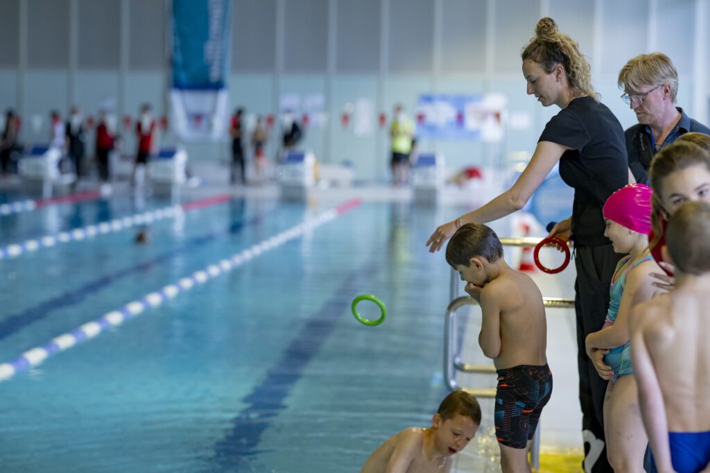 Freiwasserschwimmerin Leonie Beck unterstützt bei den Schwimmabzeichentagen 2026 und wirft einen Tauchring ins Wasser