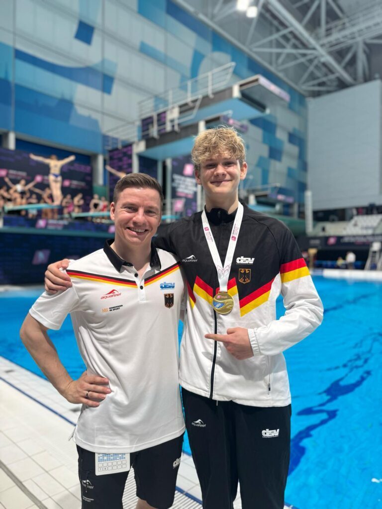 Wasserspringer Rudi Bollmann aus Dresden mit der Goldmedaille von der JEM 2026 und mit seinem Trainer Martin Wolfram