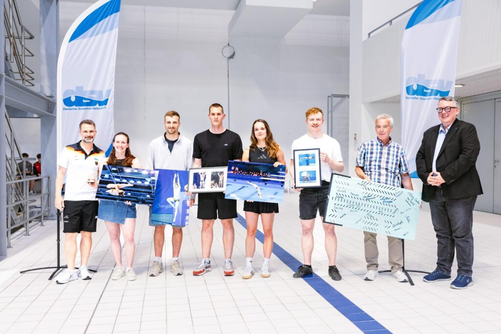 Gruppenbild bei den Deutschen Meisterschaften 2026 in Berlin mit Wassersprung-Bundestrainer Christoph Bohm, den ehemaligen Springern Jana Lisa Rother, Alexander Lube, Lars Rüdiger, Saskia Oettinghaus und Frithjof Seidel, mit Wissenschaftler Dr. Thomas Köthe vom IAT in Leipzig und mit David Profit als Präsidenten des Deutschen Schwimm-Verbandes