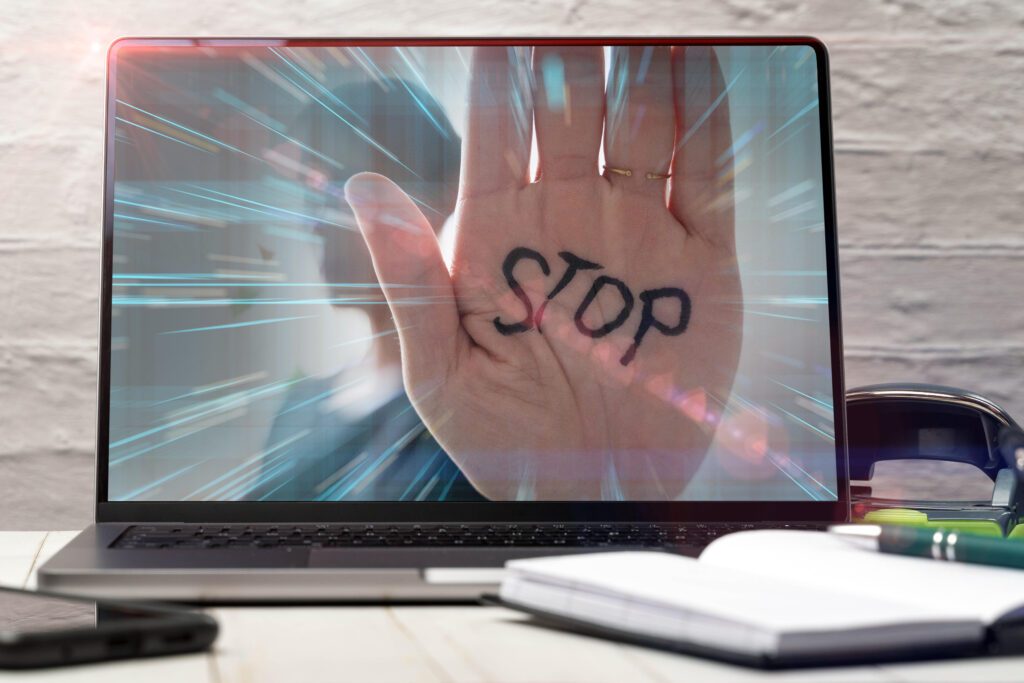 Eine Hand mit dem Wort Stop erscheint auf einem Laptopbildschirm und symbolisiert digitale Gewalt im Internet. Das Bild steht für Cybermobbing, Online-Hass und den wachsenden Bedarf an Schutz, Aufklärung und Gegenmaßnahmen.
