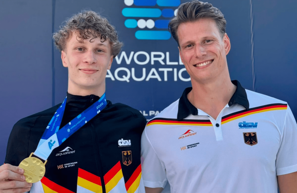 Wasserspringer Finn Awe aus Rostock mit Trainer Lucas Orlowski und der Goldmedaille von der Junioren-WM 2026 vom Wettbewerb vom 3m-Brett