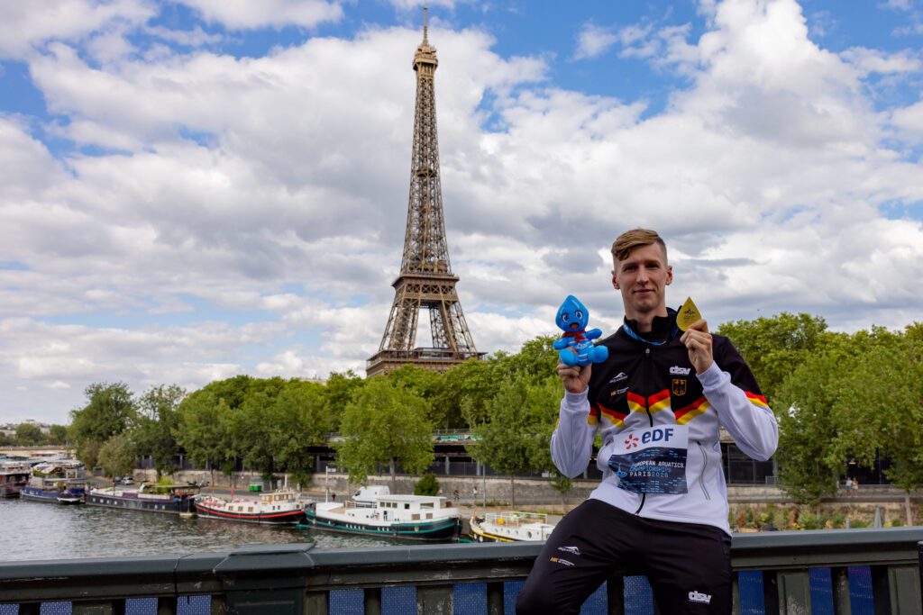 Florian Wellbrock präsentiert seine Goldmedaille vor dem Paris Eiffelturm